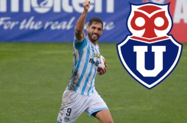 Joaquín Larrivey celebrando un gol con Magallanes junto al escudo de Universidad de Chile.