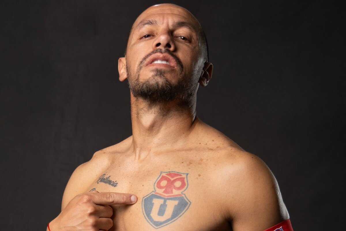 Primer plano de Marcelo Díaz apuntando el tatuaje de Universidad de Chile en su pecho.